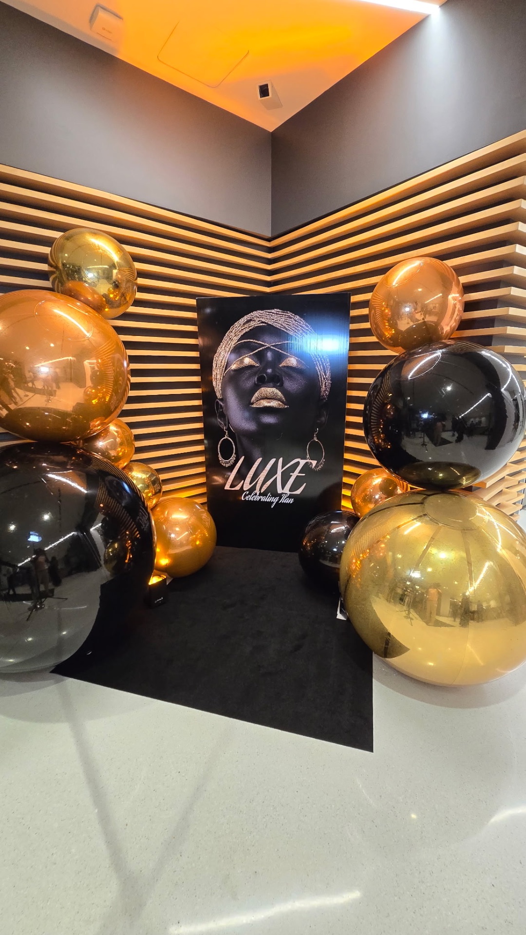 Luxe Celebrating Ikan portrait backdrop framed by gold, black and copper orbz balloons